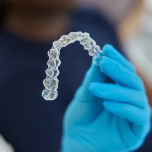 Clear Invisalign aligner held by a dental professional, showcasing Invisalign treatments in Glendale